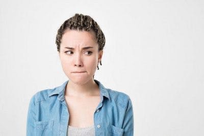 Une femme gardant intentionellement la bouche fermée regard au côté lorsqu'elle se demande : comment est-ce qu'on peut commencer à récupérer la parole si l'on ne peut pas du tout parler ?