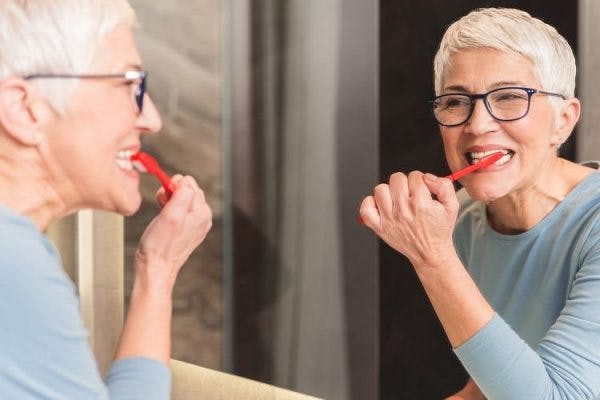 Une patiente qui brosse les dents symbolise le sujet de cet article : comment faciliter les tâches journalières après un AVC.