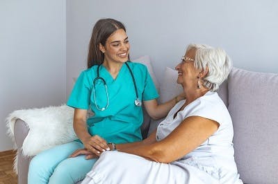 Une soignante aide sa patiente à effectuer les tâches journalières au domicile : ce qui est rendu plus facile grâce à la physiothérapie et l'ergothérapie.