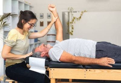 Une thérapeute aide son patient à faire des exercices passifs qui, même qu'on ne les effectue pas tout seul, aide à stimuler le cerveau et à activer la neuroplasticité.