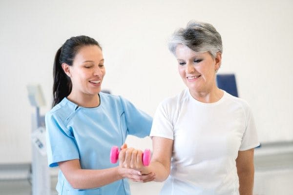 therapist teaching client about "use it or lose it" to promote recovery after neurological injury