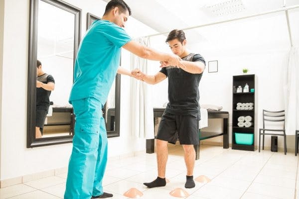 specialist helping patient at physiotherapy for spinal cord injury patients