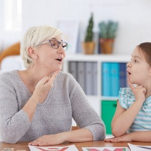 speech therapist helping girl with cerebral palsy manage motor impairments of the face