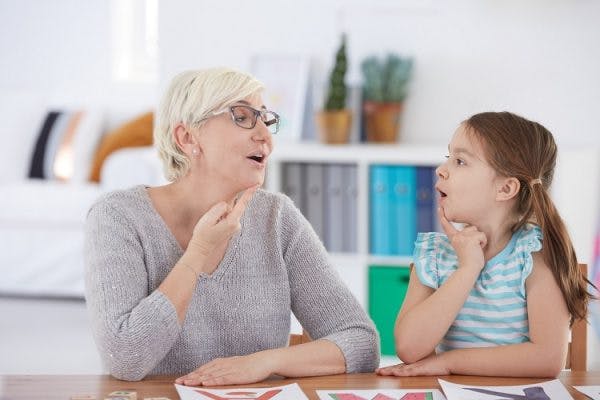 speech therapist helping girl with cerebral palsy manage motor impairments of the face