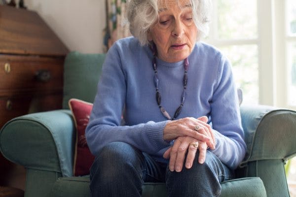 woman holding her shaking arm from clonus after stroke