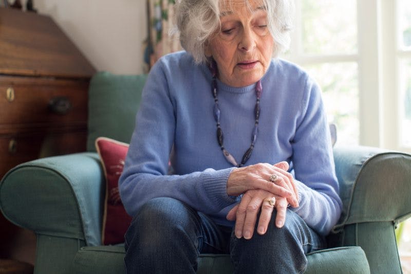 woman holding her shaking arm from clonus after stroke