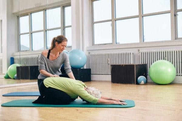 yoga therapist working with elderly stroke patient on adapted yoga pose